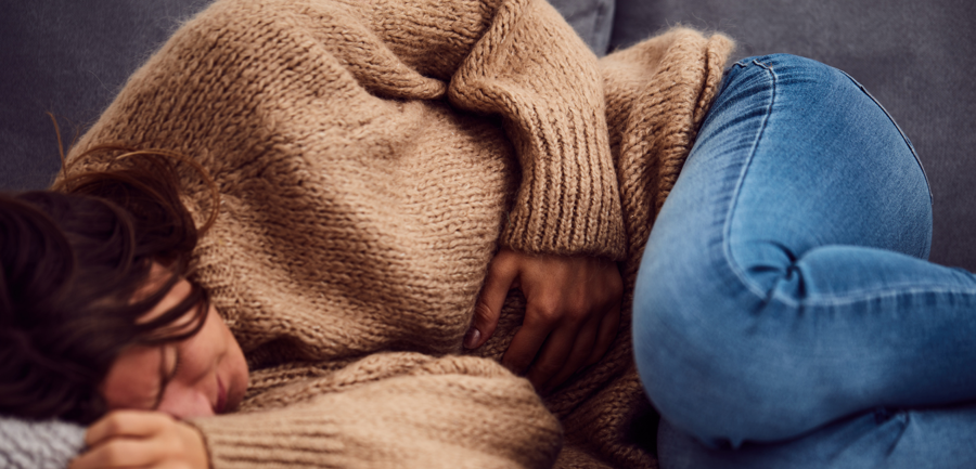 Young woman on a sofa holding her stomach