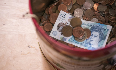 UK coins and a five pound note in a tin
