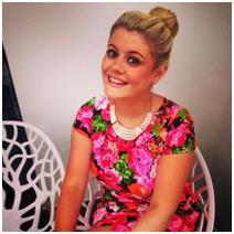 Image of Charlotte Guinea sitting down smiling in a floral dress.