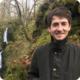 Marcus in front of a waterfall in the woods.