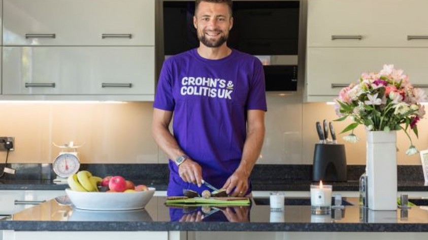 Guy Cooking In Kitchen Wearing Crohn's & Colitis Top