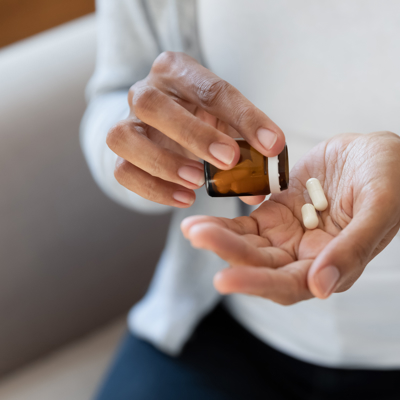 Close up of hands of a mixed race person tipping two tablets out of a tablet bottle