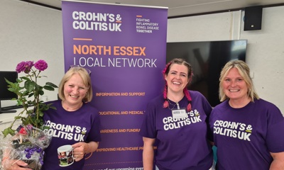 Three volunteers smiling in front of North Essex Local Network banner