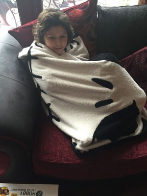 Ben wrapped in a blanket on a sofa.
