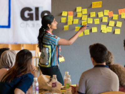 Person putting post-it notes on board in front of group