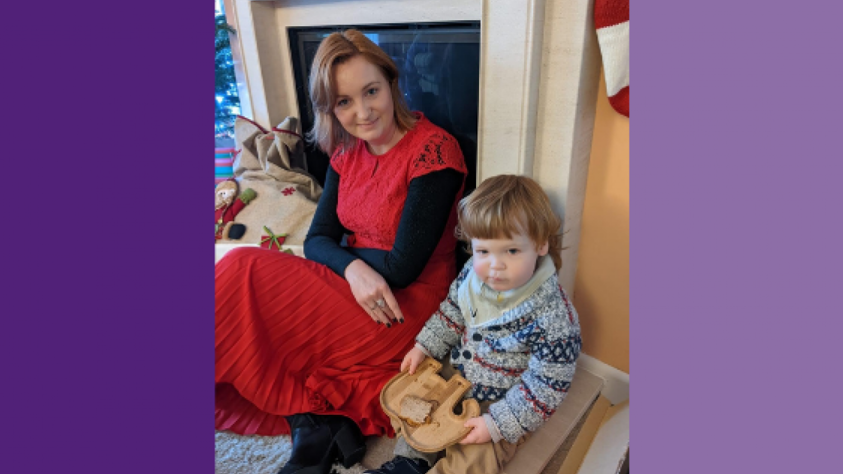 Rebecca sitting on the floor with Oliver, who is holding an elephant-shaped plate with a sandwich on 