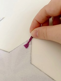 Sticking purple thread to a point of a white felt star.