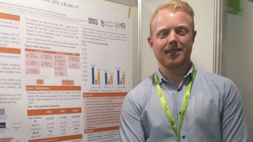 Guy Talking In Front Of Poster