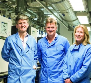 Three people wearing lab coats in a facility