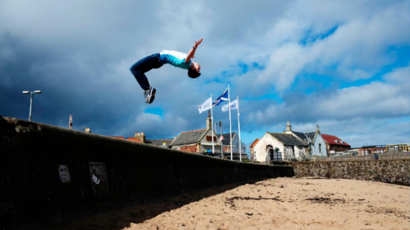 Adult male doing a backflip on the beach