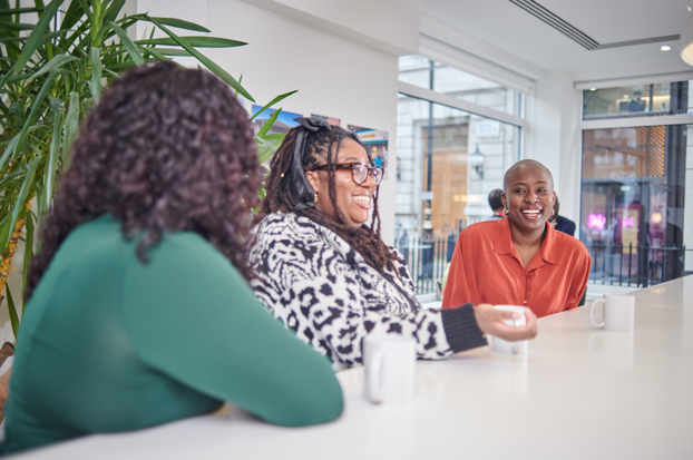 Group of Black women laughing together drinking coffee