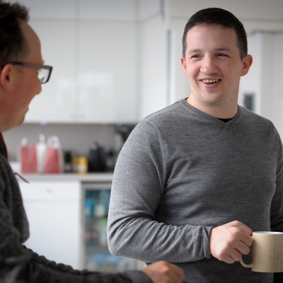 Two men with mugs chatting