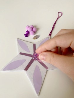 Sticking a flower on to the middle of a star decoration.