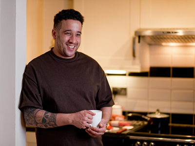 Man in kitchen at home with a mug of tea